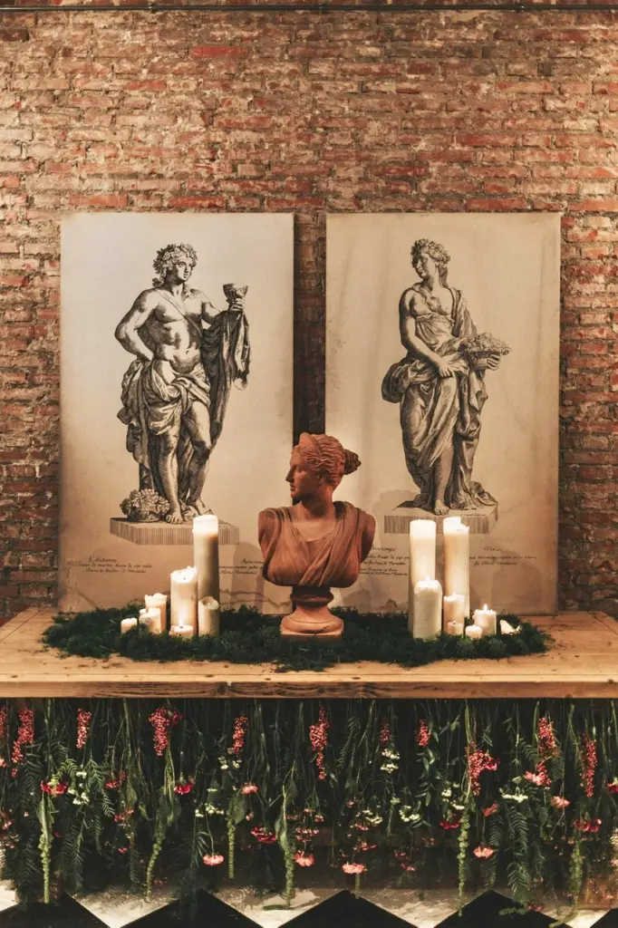 Mesa decorada con velas, un busto de terracota y una base de verde