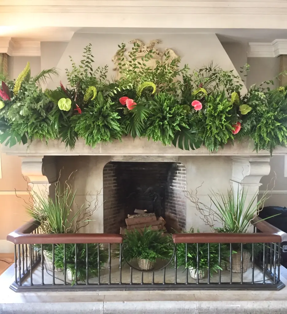 Chimenea decorada con una guirnalda de helechos, anthuriums y calas