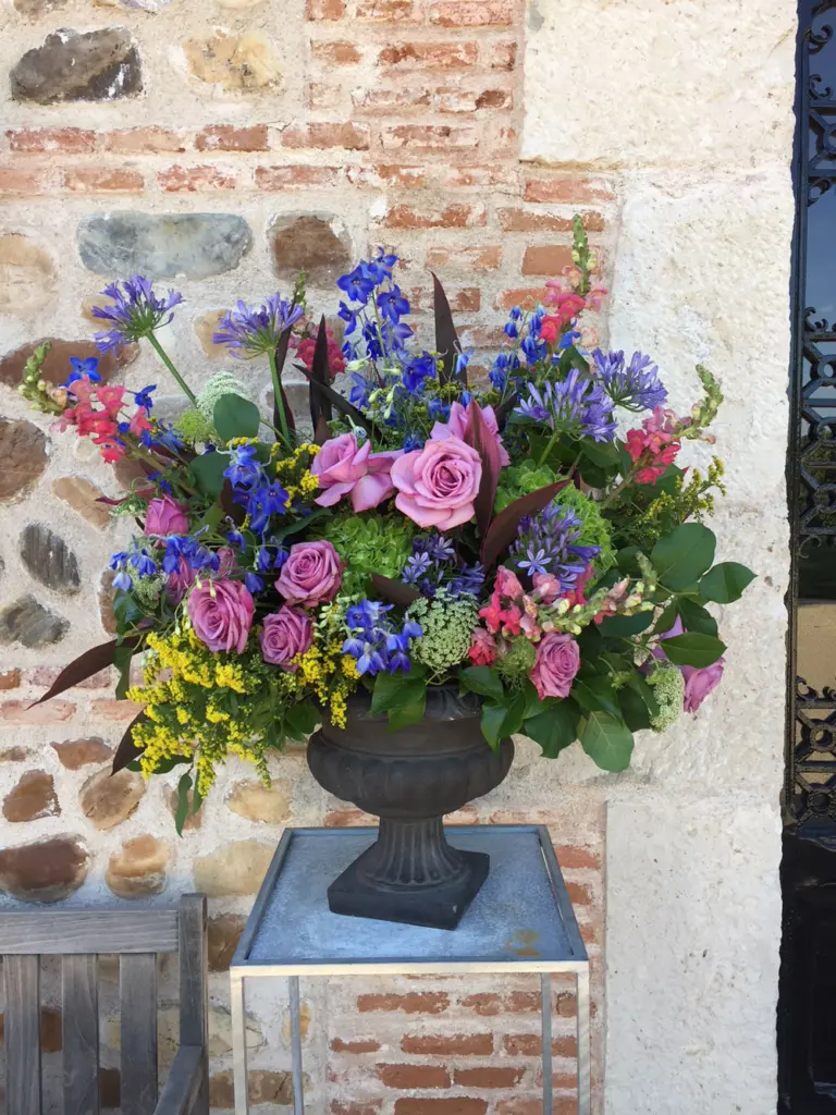 Copa de hierro con un arreglo de rosas, agapantos y delphinium en tonos rosa y azul