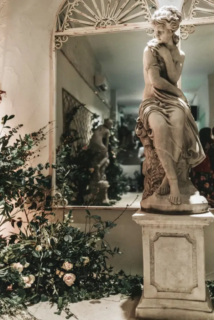 Escultura clásica rodeada de plantas en un salón