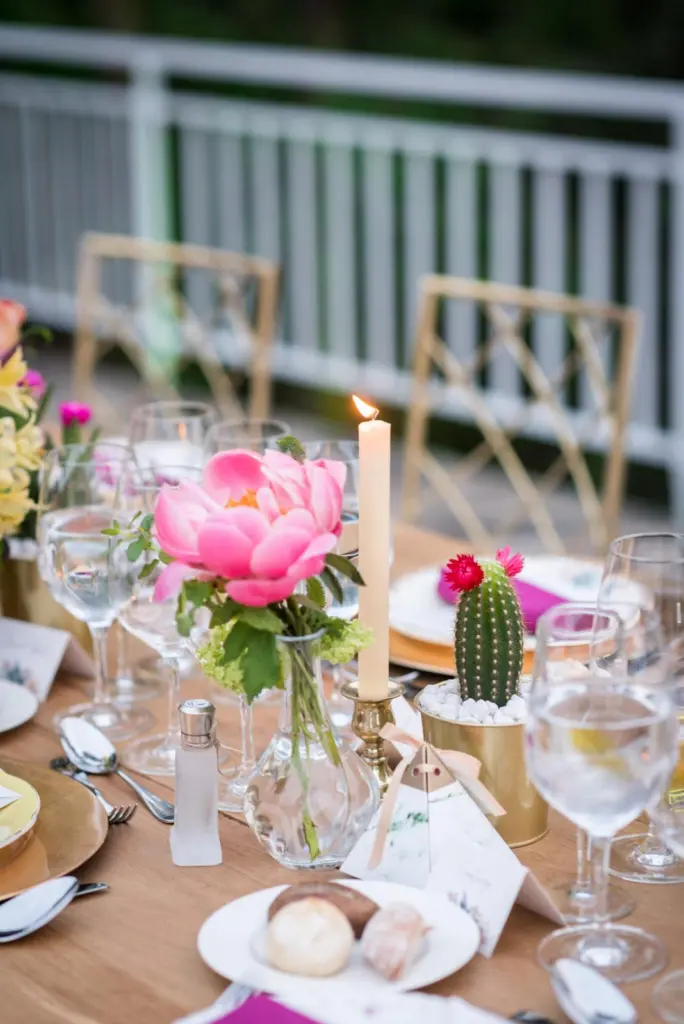 Centro de mesa con una peonía rosa, una vela y un cactus en maceta dorada