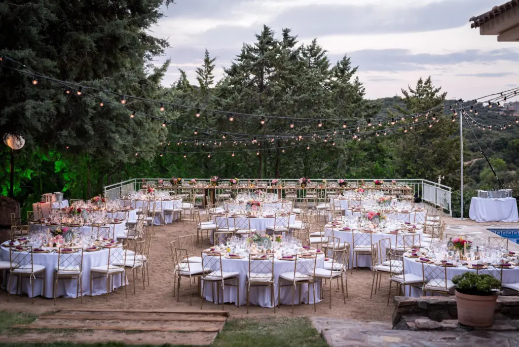 Banquete al aire libre con mesas redondas y guirnaldas de luces