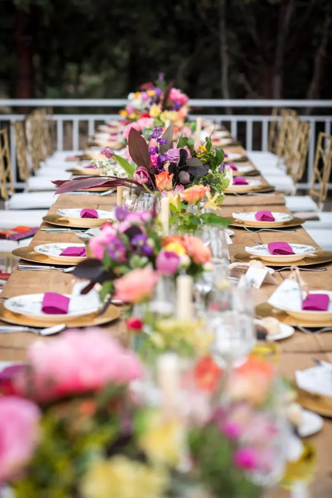 Mesa imperial con un camino de flores rosas y fucsias y bajoplatos de mimbre
