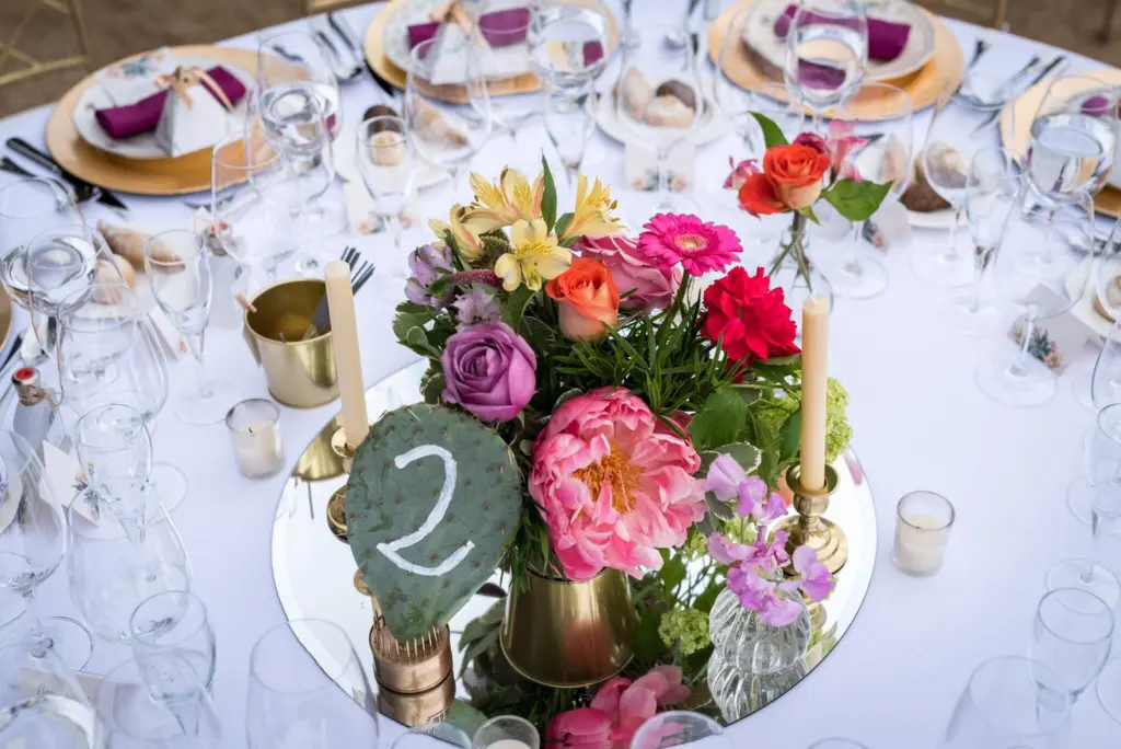 Centro de mesa de peonías, rosas y alstroemerias con el número de mesa en una hoja de nopal