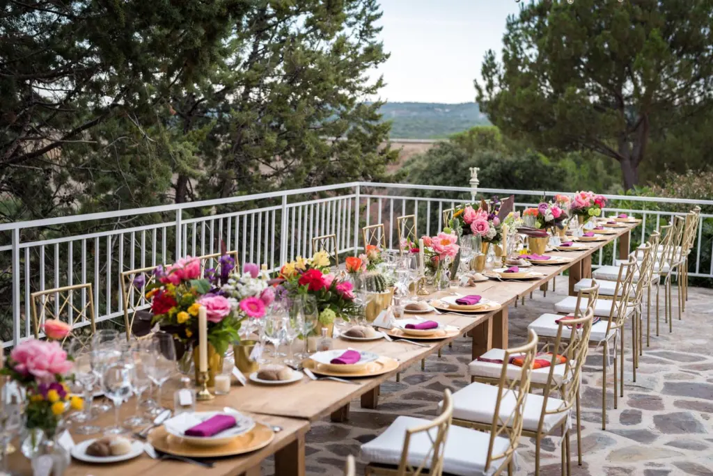Mesa imperial en una terraza con vistas, decorada con centros de flores de colores vivos