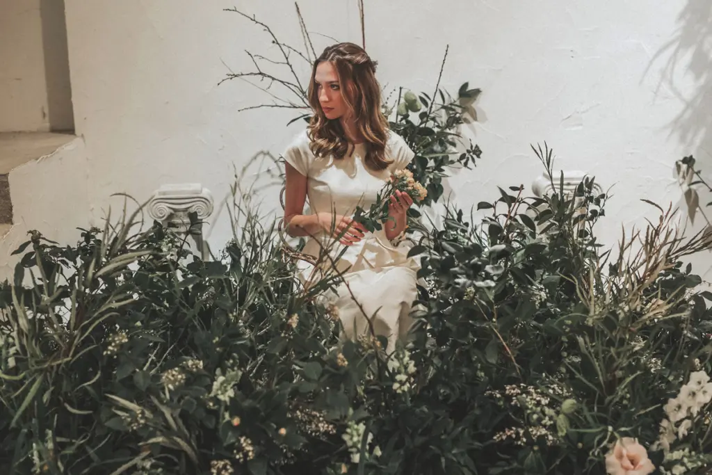 Novia rodeada de composiciones de follaje verde