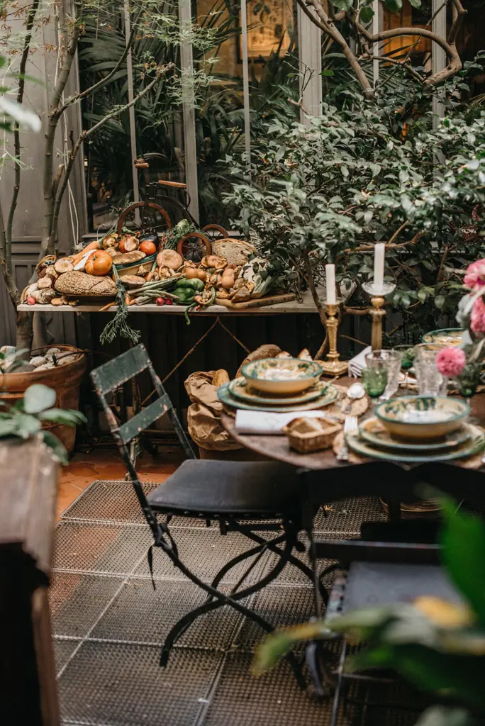 Mesa de bufé con panes y vajilla de cerámica pintada, decorada con velas y verde