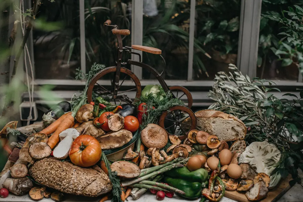 Bodegón de verduras, setas y pan junto a una bicicleta antigua