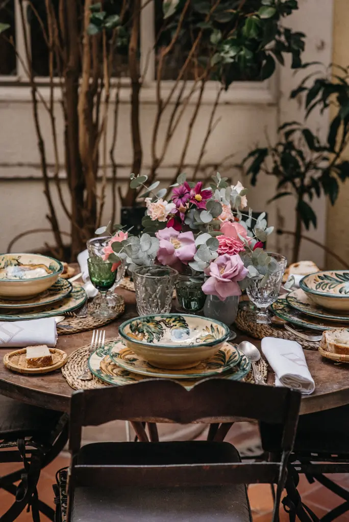 Mesa con un centro floral en tonos rosa y lila y vajilla de cerámica