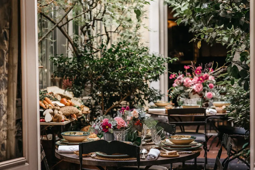 Mesas de un invernadero decoradas con centros de flores rosas y plantas