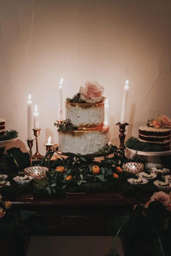 Tarta nupcial rústica decorada con una rosa, velas y cítricos