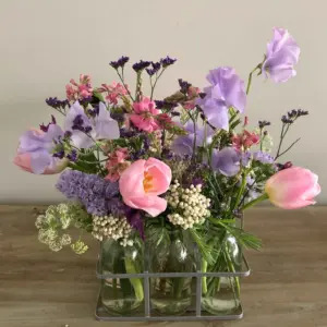 Botellitas de cristal con flores coloridas en tonos alegres