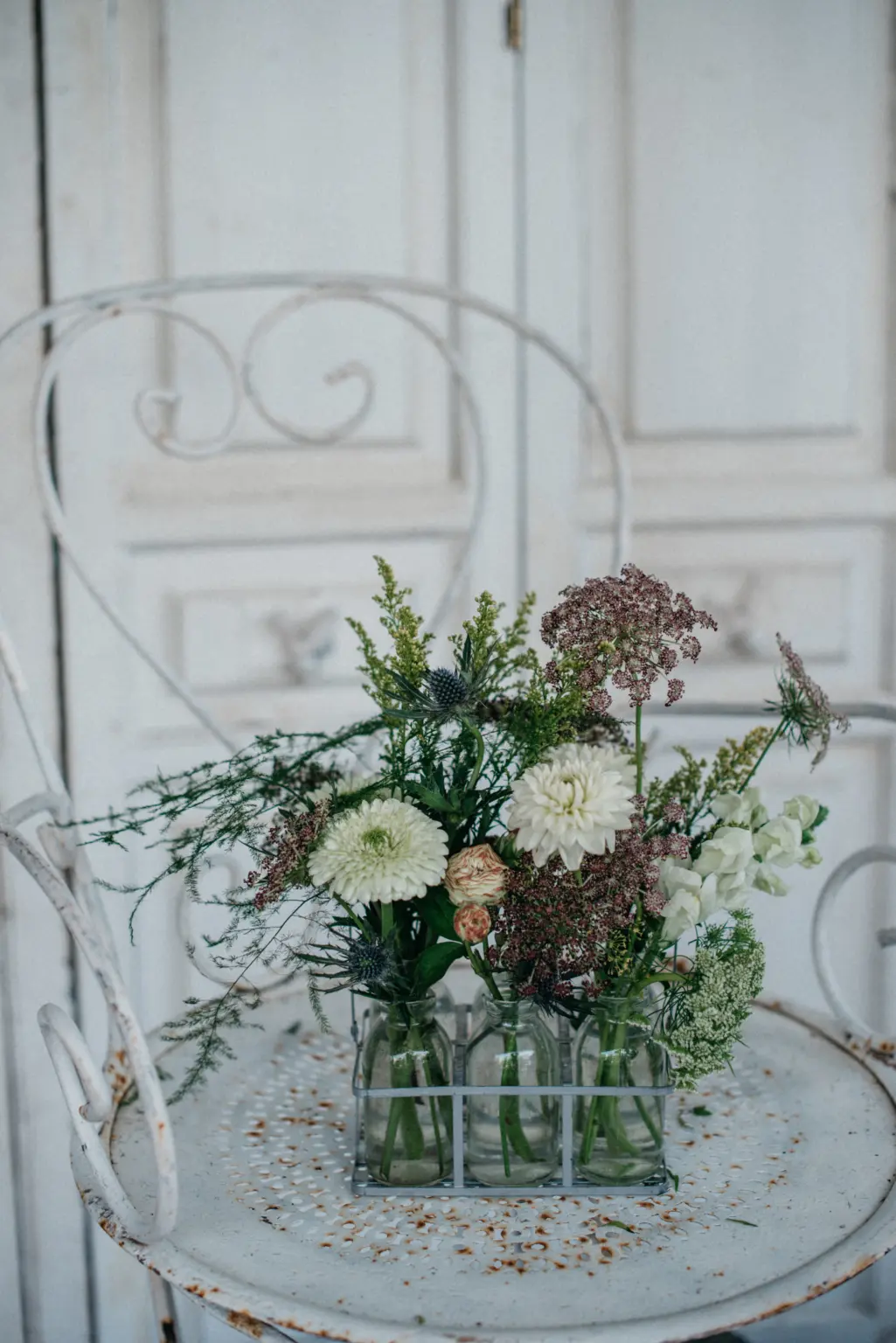 Botellitas de cristal con flores en tonos blancos y verdes