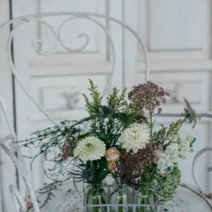 Botellitas de cristal con flores en tonos blancos y verdes