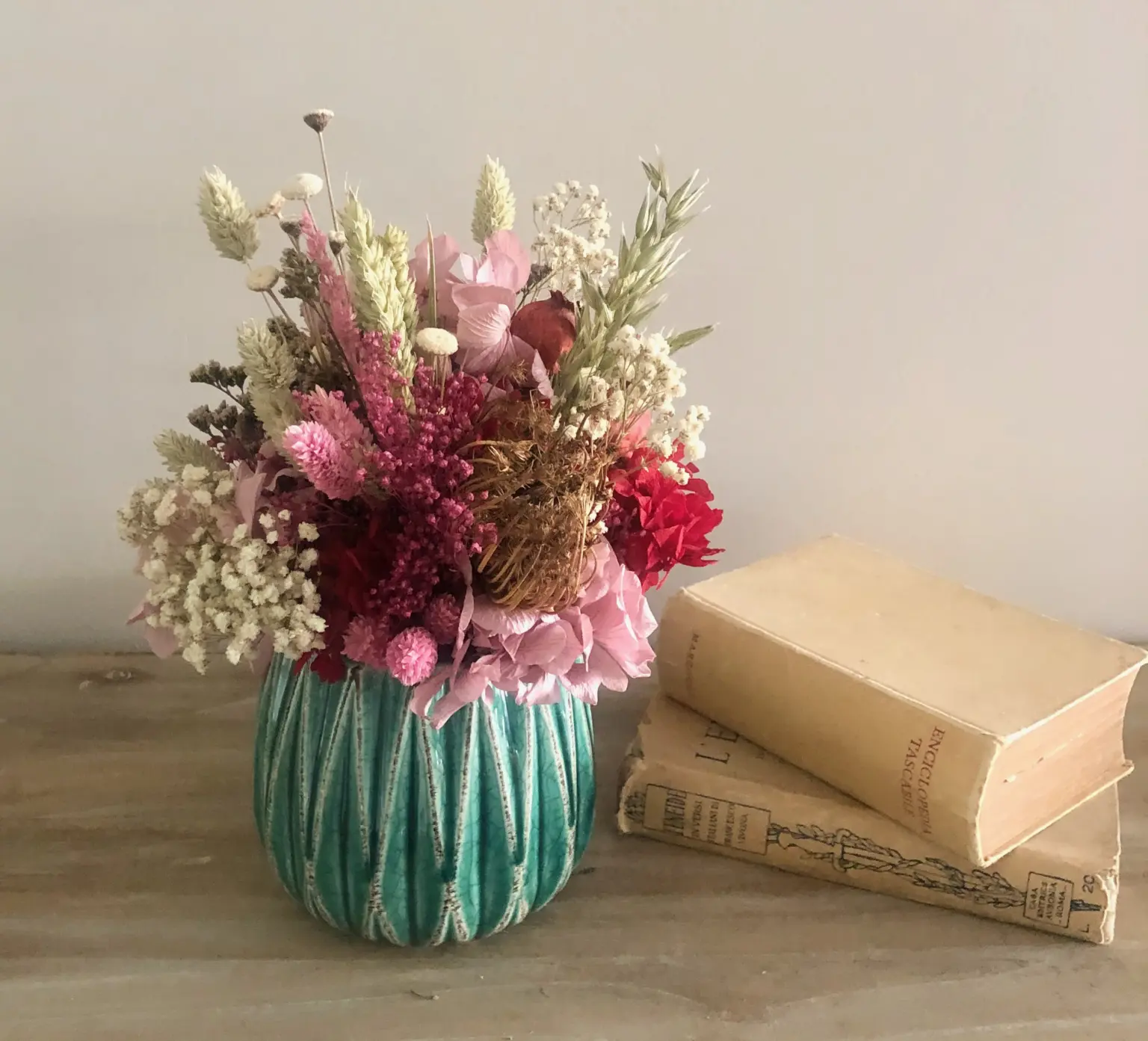 Maceta verde decorativa con plantas en tonos alegres y vibrantes