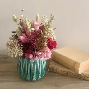 Maceta verde decorativa con plantas en tonos alegres y vibrantes